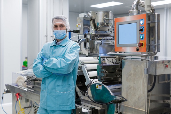 Person beside pharmaceutical manufacturing equipment