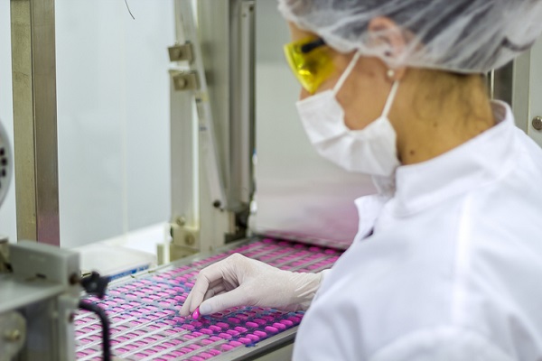 Person analyzing pharmaceuticals in manufacturing line